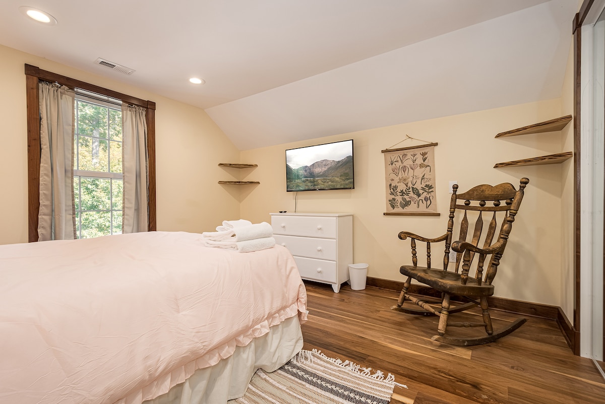 Soft bedroom with blush bedding, wood trim, and rocking chair